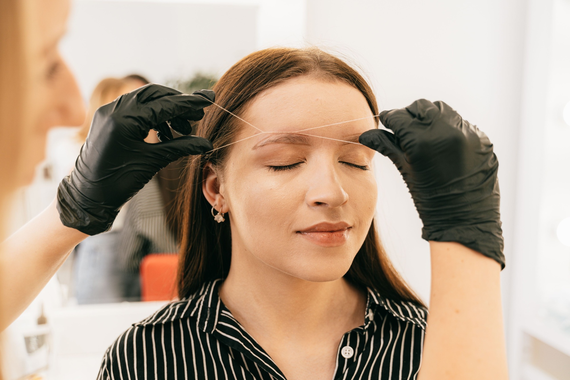 Beauty professional performing threading treatment